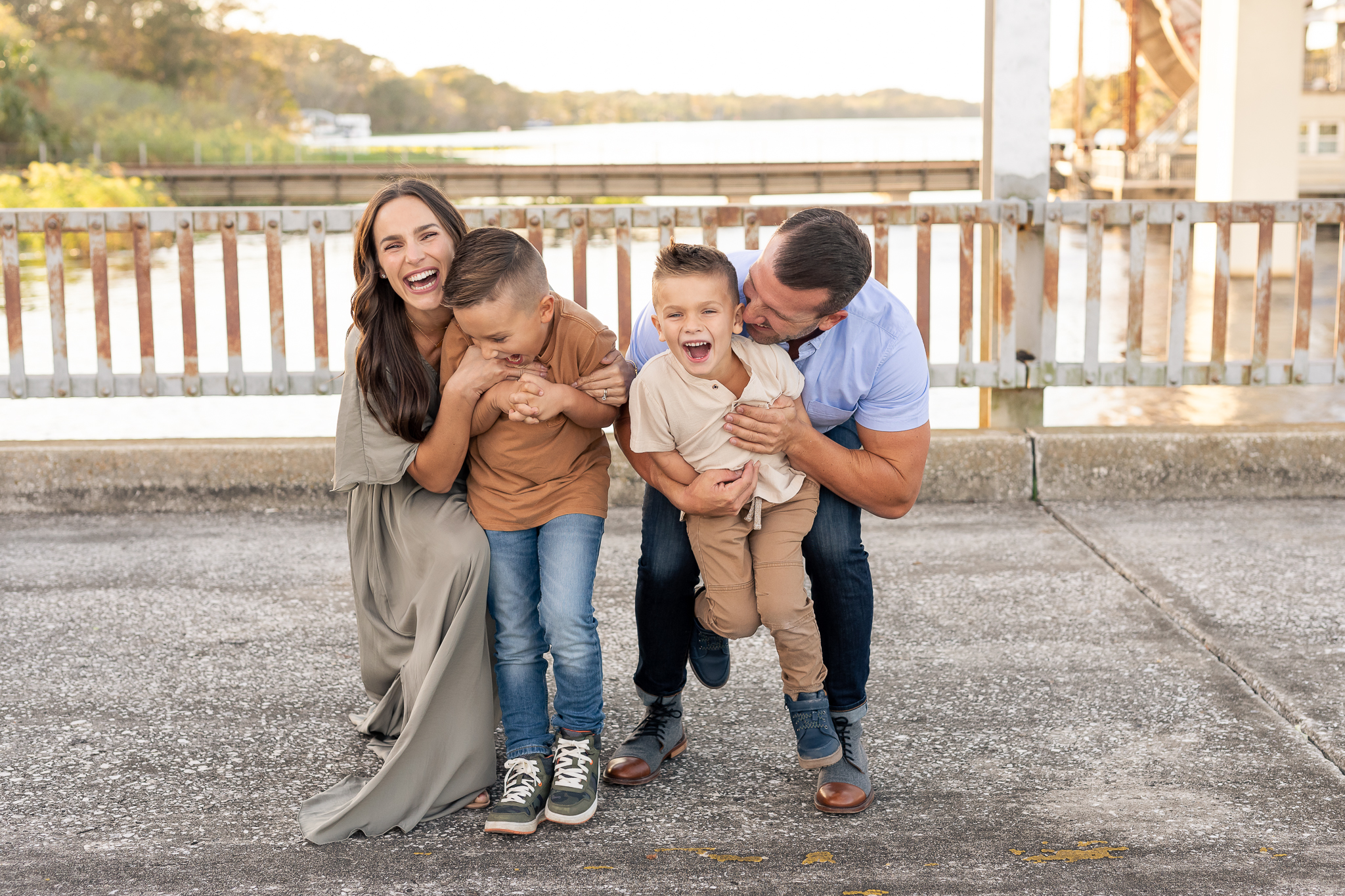 A family of four with two young children playing a game. The parents came from behind without them knowing and gave them a huge hug showing the family connection at their fall family photo session in Lake Mary, Florida.