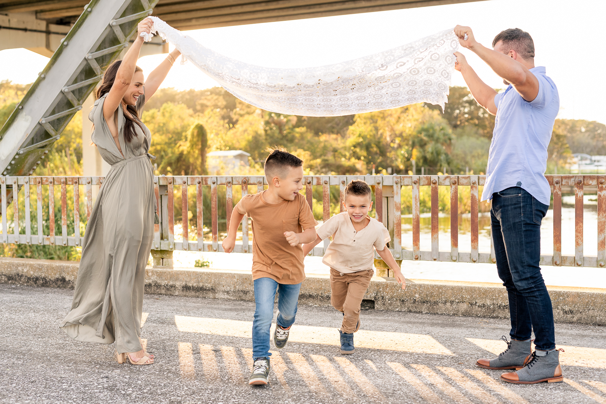 A family of four with two young children running under the blanket during their fall family photo session in Lake Mary, Florida.